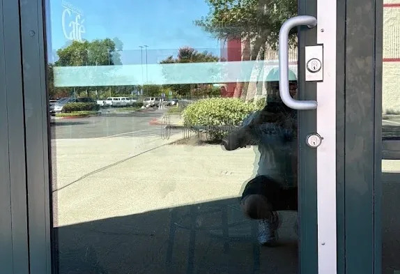 Glass storefront entrance with a commercial pull handle and deadbolt.