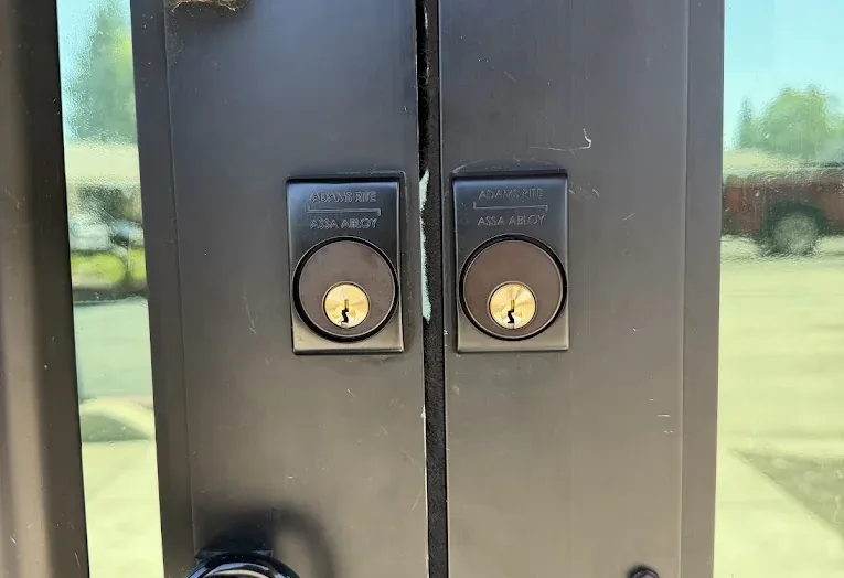 Two Adams Rite mortise locks and pull hardware on a commercial entrance.