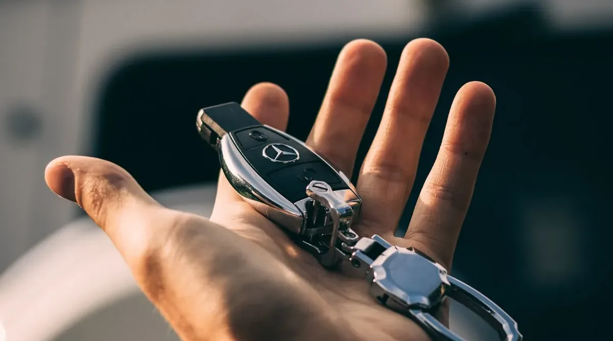 Automotive keys and a remote fob held in a customer’s hand.