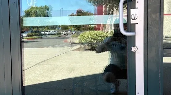 Glass storefront entrance with a commercial pull handle and deadbolt.