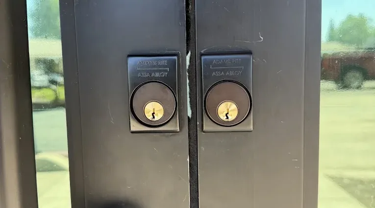 Two Adams Rite mortise locks and pull hardware on a commercial entrance.