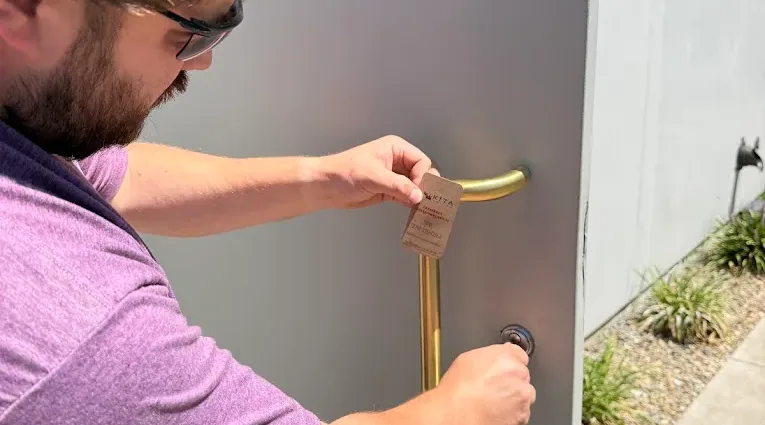 Technician fitting door hardware at an exterior entry.