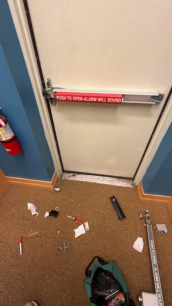 Tools laid out at the foot of a commercial doorway during hardware work.