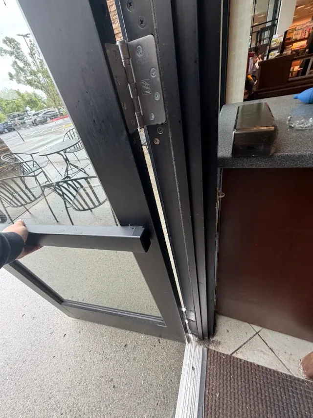 Close-up of the lower hinge and threshold on a glass door.