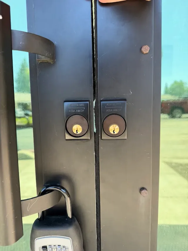 Two keyed cylinders fitted to a pair of commercial doors, with a combination padlock on the handle