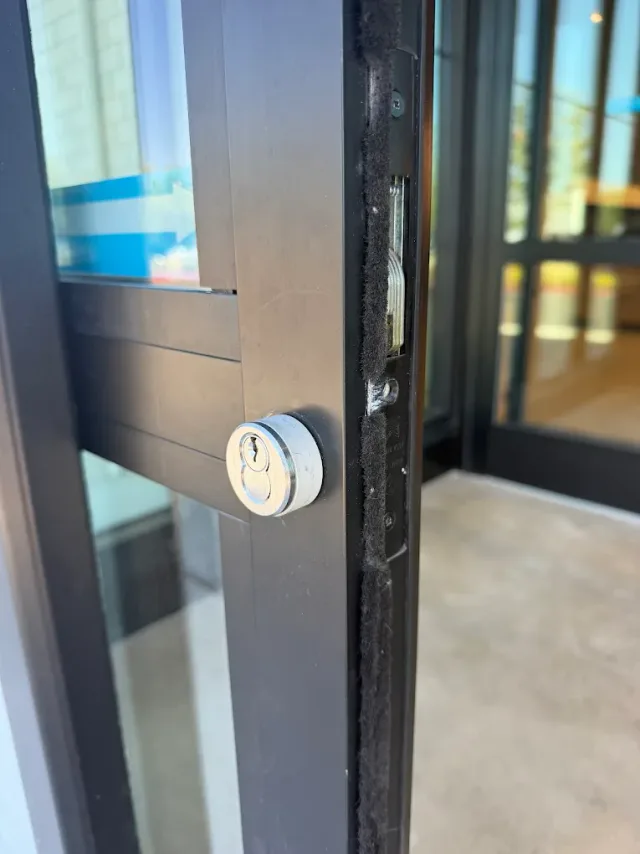 Electronic entry lock mounted on a dark-framed commercial door.