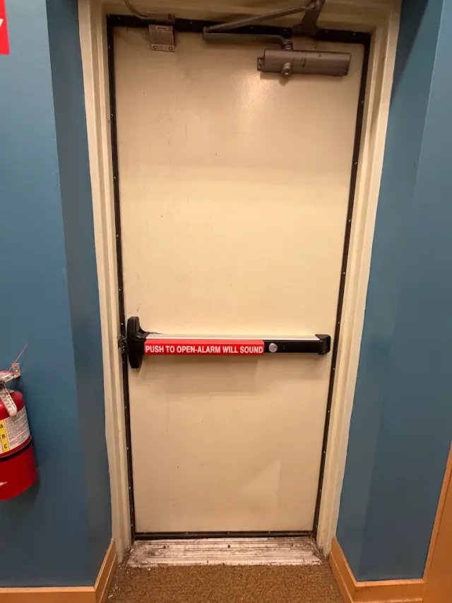 Panic-bar exit door and tools on the floor during a service visit.